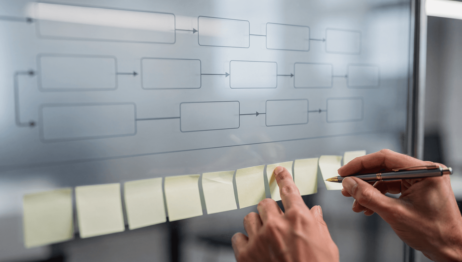 A 30-day operational plan taking shape on a glass planning board, a swim-lane process diagram of empty boxes and arrows above a row of blank sticky notes being arranged into sequence, cool blue-grey tones with a single warm brass highlight on a pen.